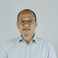 Two men sat at a table chatting and smiling to the camera