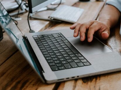 Close up image of a hand hovering over a laptop keyboard