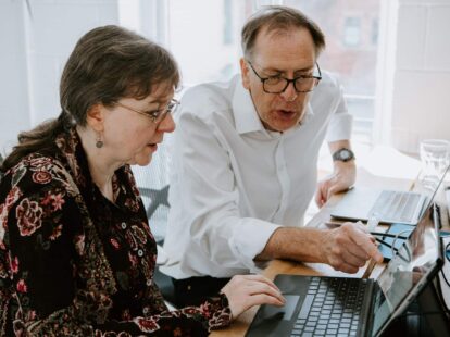 Image of a man and women leaning over a laptop talking
