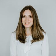 Two men sat at a table chatting and smiling to the camera