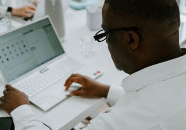 Image shot from behind of a man typing on a laptop