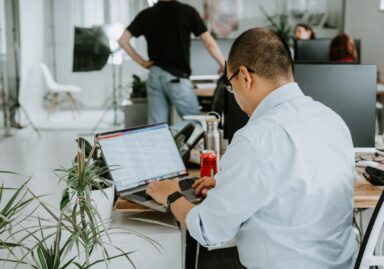 Image from behind of a man conducting research on a laptop