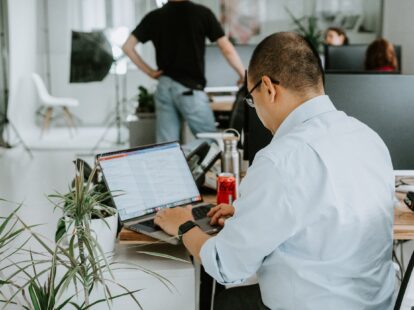 Image from behind of a man conducting research on a laptop