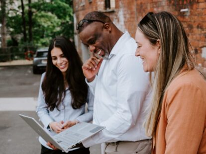 Image of a group of people outside looking at a laptop